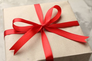 Kraft kağıdına sarılı hediye, gri desenli arka plan, yakın plan.