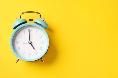 Sarı arka planda turkuaz alarm saati, üst manzara. Metin için boşluk