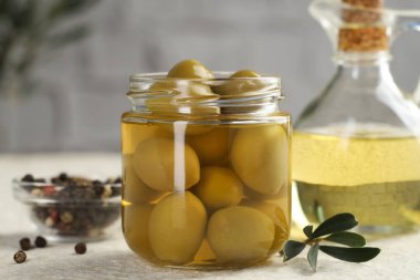 Kavanozda turşulu yeşil zeytin, beyaz desenli masada yağlı ve biberli mısır, yakın plan.