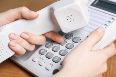 Ahşap masada telefonu olan kadın, yakın plan.