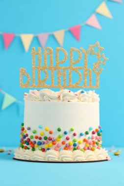 Renkli süslemeli nefis bento keki açık mavi masada, yakın plan.