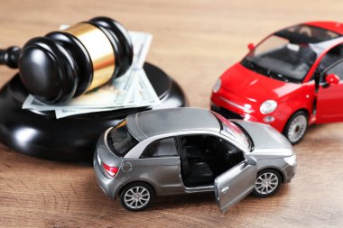 Trafik kazası yasası. Yargıç tokmağı, oyuncak arabalar ve paralar ahşap masada, yakın plan.