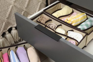 Organizers with folded clothes in drawer indoors, closeup