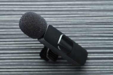 Lavalier mikrofonu siyah ahşap masada, yakın plan.