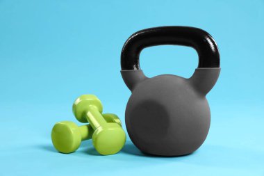 Açık mavi arkaplanda kettlebell ve dambıllar