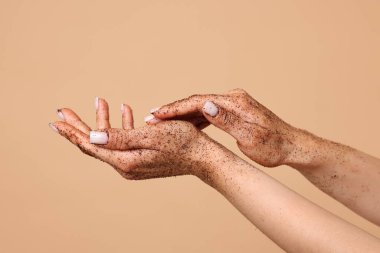 Bej arka planda ellerini ovuşturan kadın, yakın plan.