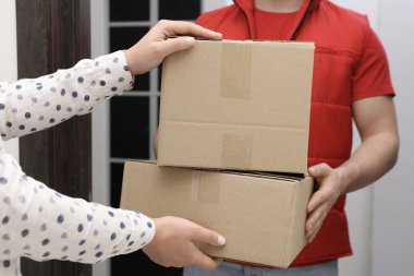 Kurye içerideki alıcıya paketler veriyor, yakın plan.