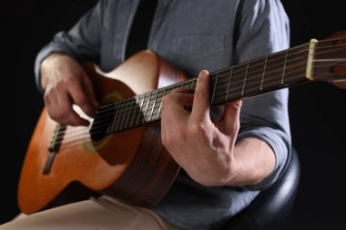 Siyah arka planda gitar çalan adam, ele odaklan.