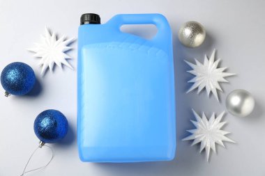 Plastik şişede antifriz, takılar ve gri arka planda dekoratif kar taneleri.