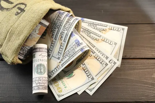 Üzerinde dolar banknotları olan para çantası. Gri ahşap masa, yakın plan.