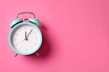 Pembe arka planda turkuaz alarm saati, üst manzara. Metin için boşluk