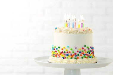 Renkli serpiştirilmiş nefis bento keki ve bulanık beyaz arka planda yanan mumlar. Yakın plan. Metin için boşluk