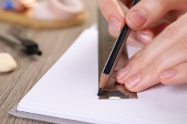 Ahşap masada cetvel ve kalemle çizim yapan kadın, yakın plan.