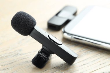 Lavalier mikrofon ve ahşap masada kablosuz alıcısı olan akıllı telefon.