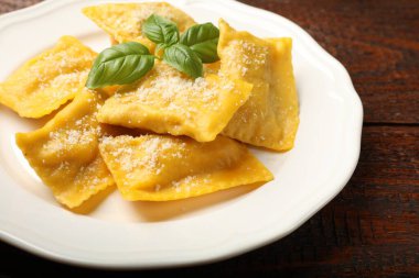 Ahşap masada parmesan peynirli ve fesleğenli lezzetli ravioli, yakın plan.