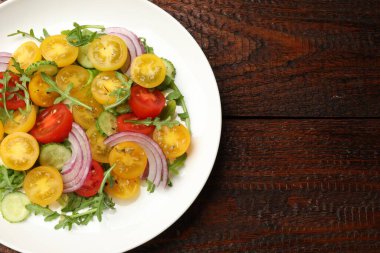 Tahta masanın üstünde sarı domatesli taze salata, üst manzara. Metin için boşluk