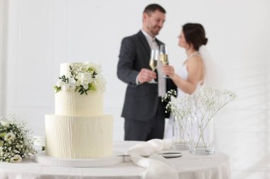 Mutlu evli çift içeride, düğün pastasına ve masadaki bukete odaklan.