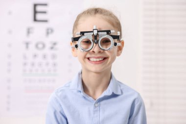 Göz doktorunun muayenehanesinde görüş testinin yanında mahkeme çerçevesi olan küçük bir kız.