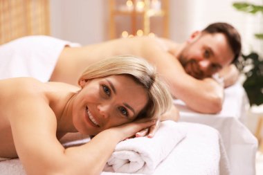 Spa salonundaki masaj masalarında uzanan mutlu çift, seçici odak