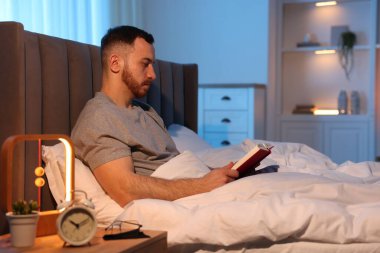 Genç adam evde yatakta kitap okumak