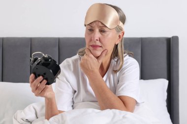 Evde yatağında çalar saati olan uyuyakalmış bir kadın.