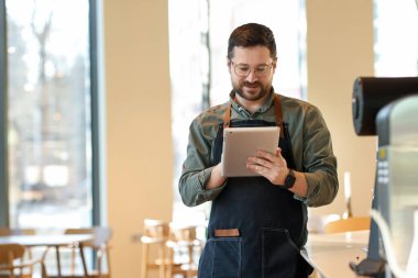 Kafesinde tabletle çalışan yakışıklı bir işletme sahibi. Metin için boşluk