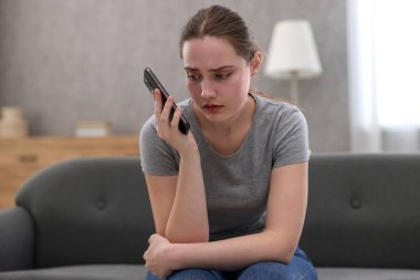 Depresyondaki kadın evdeki kanepede ruh sağlığı için yardım hattını arıyor.