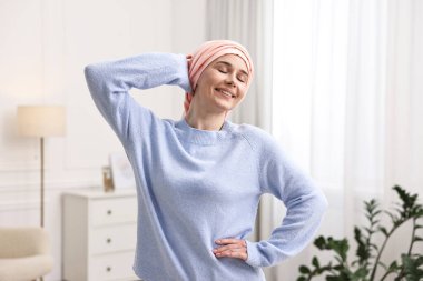 Kapalı alanda türbanlı kanserli gülümseyen kadının portresi.