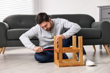 Evdeki tornavidayla tahta tabureyi tamir eden adam.