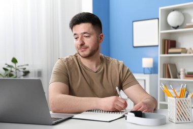 İçerideki masada ders sırasında not alan bir adam. Kendi kendine çalışma.