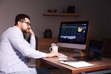 Borsa. Kapalı alandaki bilgisayarda finansal piyasayı analiz eden adam.