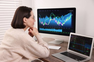 Borsa. Ahşap masa içerisindeki bilgisayarda finans piyasasını analiz eden kadın.