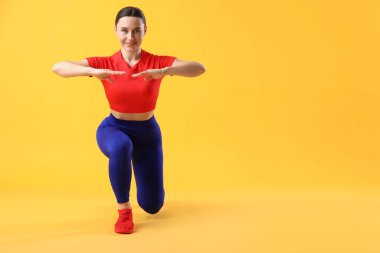 Spor giyimli kadın turuncu arka planda egzersiz yapıyor, metin için boşluk var.