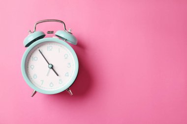 Pembe arka planda turkuaz alarm saati, üst manzara. Metin için boşluk