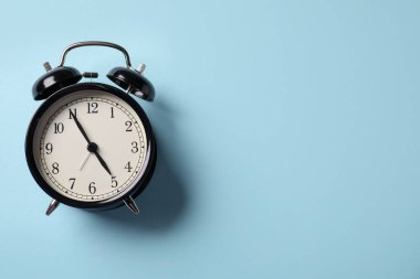 Açık mavi zemin üzerinde siyah alarm saati, üst manzara. Metin için boşluk