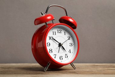 Gri arkaplana karşı ahşap masada bir kırmızı alarm saati