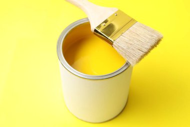 Sarı arka planda parlak boya ve fırça kutusu, yakın plan.