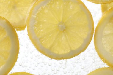 Arka planda limon dilimleri olan soda, yakın plan.