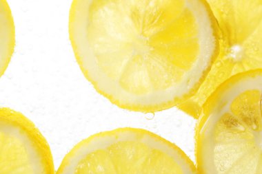 Arka planda limon dilimleri olan soda, yakın plan.