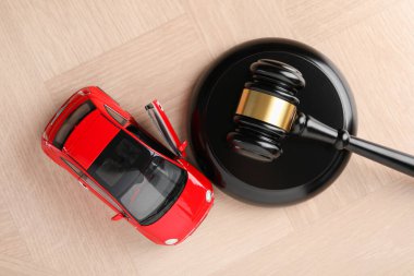 Motorlu taşıt kazası yasası. Gavel ve araba modeli ahşap arka planda, üst görünümde.