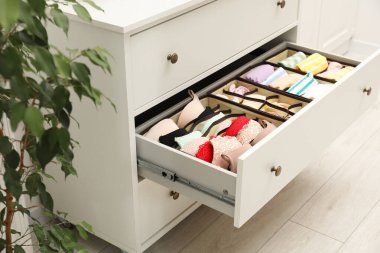 Organizers with folded clothes in drawer indoors, closeup