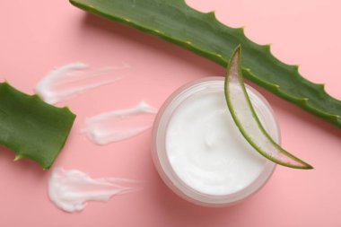 Kavanozda aloe vera özütüyle nemlendirici krem ve pembe arka planda yapraklar.