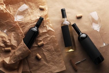 Şarap şişeleri, bardaklar, tirbuşon ve mantarlar parşömen kağıdında, düz uzanmış