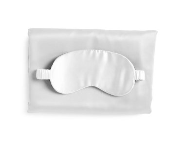 Beyaz arka planda ipek çarşaflar ve uyku maskesi, üst manzara.