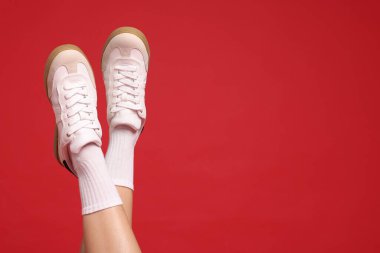 Kırmızı arka planda şık ayakkabılar giyen bir kadın, yakın plan. Metin için boşluk