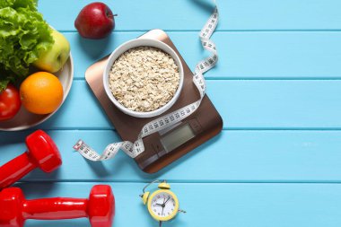 Elektronik mutfak terazisi, mezura, halterler ve ürünler açık mavi ahşap masa üzerinde düz konum. Metin için boşluk