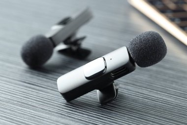 Lavalier mikrofonları siyah ahşap masada, yakın plan.