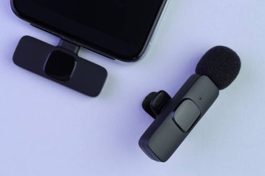 Lavalier mikrofon ve kablosuz alıcısı ışıklı arka planda, düz konum