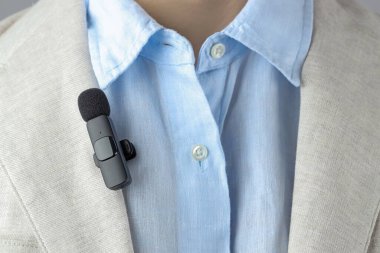 Takım elbisesine mikrofon takmış bir adam, yakın plan.