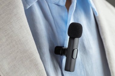 Gömleğine mikrofon takmış bir adam, yakın plan.